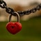 a red heart-shaped padlock hangs on a chain, a symbol of love and loyalty