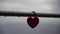 Red heart shaped padlock on metal railing of bridge. Love locks in the park - as symbols of eternal love, friendship and