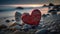 a red heart sitting on top of a pile of rocks.