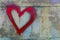 A red heart with smudges is painted on an old, shabby metal wall