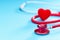 Red heart and stethoscope on on blue background.Selective focus.