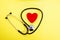 Red heart and stethoscope on yellow background, heart health care and medical technology concept, selective focus,