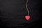 Red heart on a string on a black crumpled background.