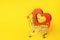 Red heart in the supermarket trolley. concept of buying love. Valentine`s Day. yellow background. Love of shopping. Favorite stor