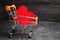 Red heart in the supermarket trolley. concept of buying love. Valentine`s Day. yellow background. Love of shopping. Favorite stor