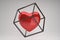 Red  heart symbol in a golden cube frame on a gray background, modern love concept.