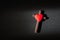 Red heart on top of wooden crucifix cross on black background