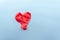 Red heart from two new, not inflated Balloons on silver paper background