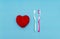 Red heart between two toothbrushes on pastel blue pink background. Male and female teeth hygiene concept. Close up. Empty place