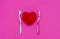 Red heart between two toothbrushes on pastel pink background. Male and female teeth hygiene concept. Close up. Empty place for