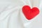 Red heart on white satin textile background