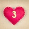 Red heart with wooden number 3 on fabric background