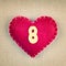 Red heart with wooden number 8 on fabric background