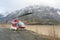 A red helicopter sits by an alpine mountain lake