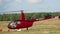 Red helicopter taking off from a field