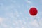 Red helium air balloon with calm blue cloudy sky on background. Peace and holiday concept. Bottom view. Copyspace for