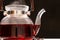 Red hibiscus tea from the petals of a Sudanese rose in a glass teapot, steam from a teapot on a black background