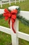 Red holiday ribbon bow green pine festoon white fence