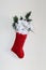 Red holiday stocking filled with white and silver flowers and pine