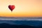 Red hot air balloon in the shape of a heart flying