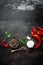 Red hot chili pepeprs and peppercorns on black metal background, top view, copy space for text