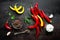 Red hot chili pepeprs and peppercorns on black metal background, top view, copy space for text