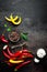 Red hot chili pepeprs and peppercorns on black metal background, top view, copy space for text