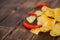 Red hot chili peppers and potato chips lie on a wooden table made of pine boards. Daylight. Close-up.