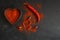 red hot chili peppers powder in heart shaped bowl on black stone table. Love concept. Top view flat lay with copy space