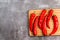 Red hot chili peppers on a rectangular cutting wooden board on a dark background