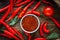 Red hot chili peppers and salsa or adjika in white ceramic bowl.
