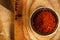 Red hot chillies pepper flakes in bowl on wooden board backgro