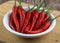 Red hot fresh bird eye chilli in white bowl on wooden background