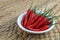 Red hot fresh bird eye chilli in white bowl on wooden background