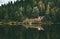 Red house in coniferous Forest with lake water reflection Landscape