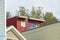 Red house in detail shot with exterior timber or wood facade and other building details in foreground midday in sun