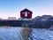 Red house on the rock near the water. The seascape with traditional red white wooden houses