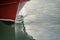 Red hull of a ship and its reflection plowing through the waters