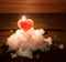 Red ice heart and the burning candle behind it on a hill of whit