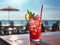 Red iced tasty cape cod sea breeze cocktail mocktail on bar deck with seashore view in the background. Generative AI