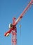 Red industrial construction crane above blue sky background