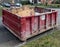 Red industrial dumpster on neighborhood street