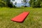 Red inflatable camping mattress on the green grass