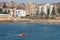 Red inflatable rescue raft sailing in water in front of city buildings in Coogee, Sydney, Australia