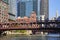 Red iron bridge over Chicago canal with skyscrapers, hotels, and parking garage in summer