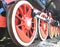 Red iron wheels of steam locomotive on rails