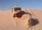 Red Jeep driving up sand dune