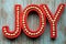 Red Joy word letters on a teal wood background, useful for rustic Christmas holiday projects