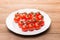 Red juicy fresh cherry tomatoes on a green branch. Tomatoes on a white plate. Free space for text. Concept - healthy food  diet