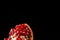 Red and juicy garnet seeds. Healthy pomegranate on a black background. A garnet piece full of sour, fresh, nutritiou